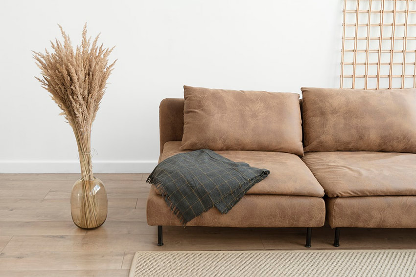 an image of a brown leather couch with a sheet hanging off of the corner